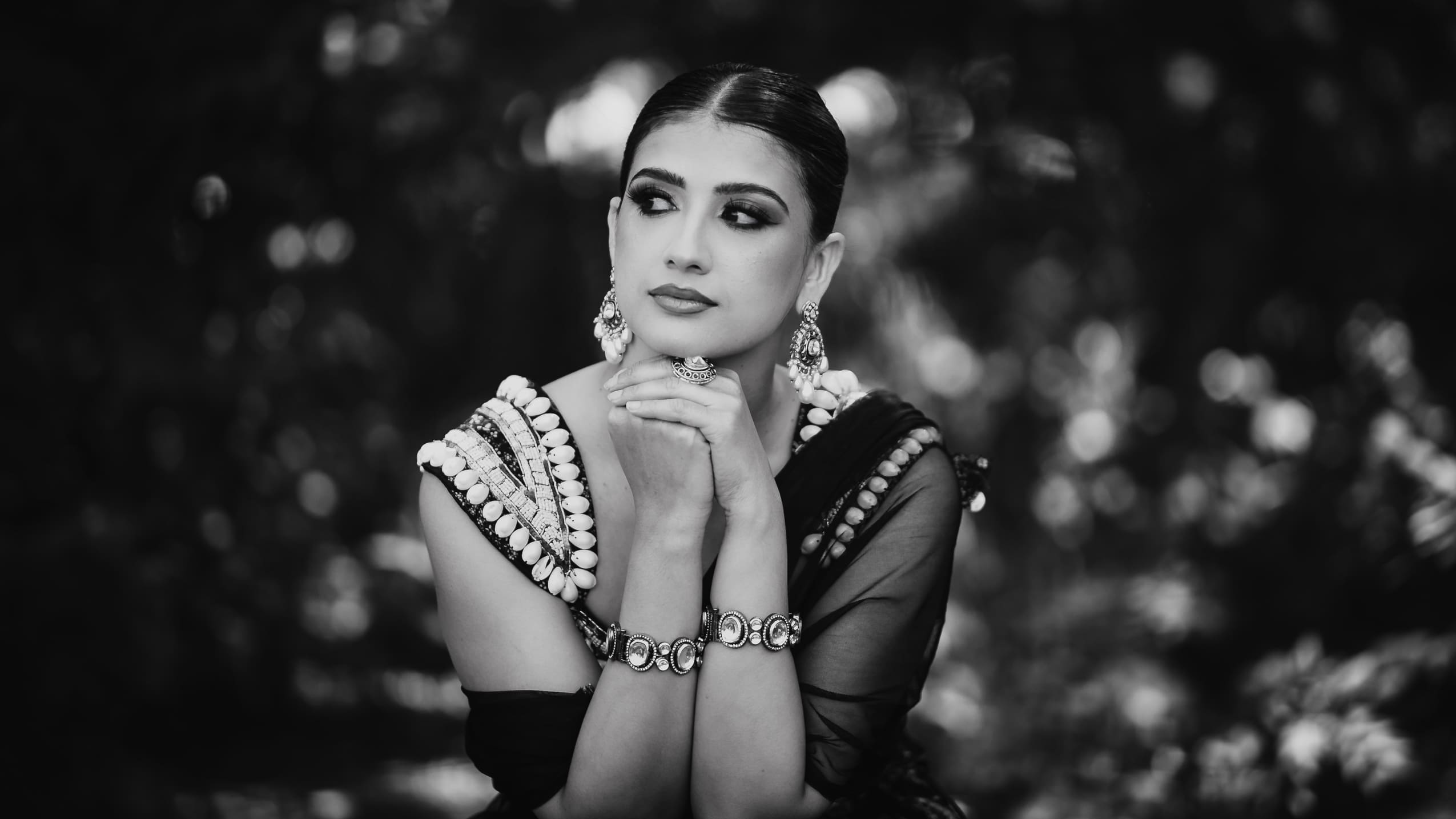 Black and white bridal portrait at Parkwood Estate in Oshawa, Ontario, bride with hands under chin wearing statement earrings and bracelets, cinematic South Asian wedding photography near Toronto and GTA.