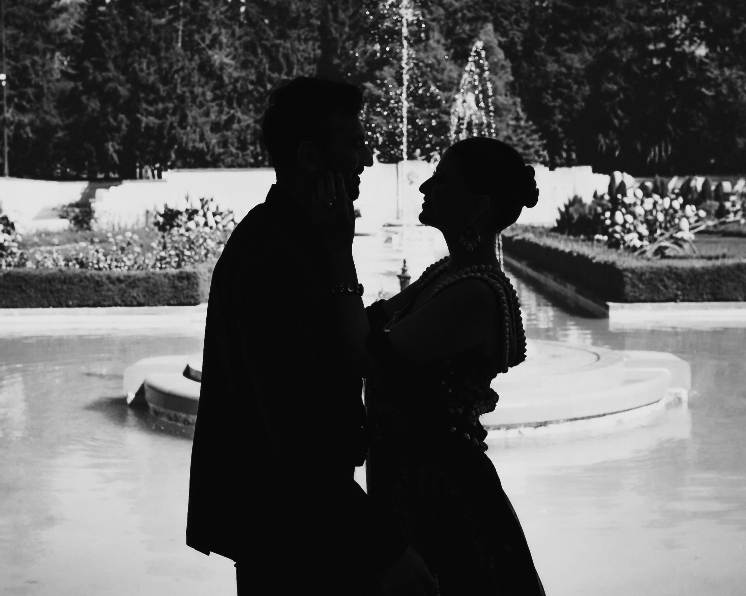 Black and white silhouette of a wedding couple embracing by the fountain at Parkwood Estate in Oshawa, Ontario, romantic cinematic portrait with water and formal gardens in the background.