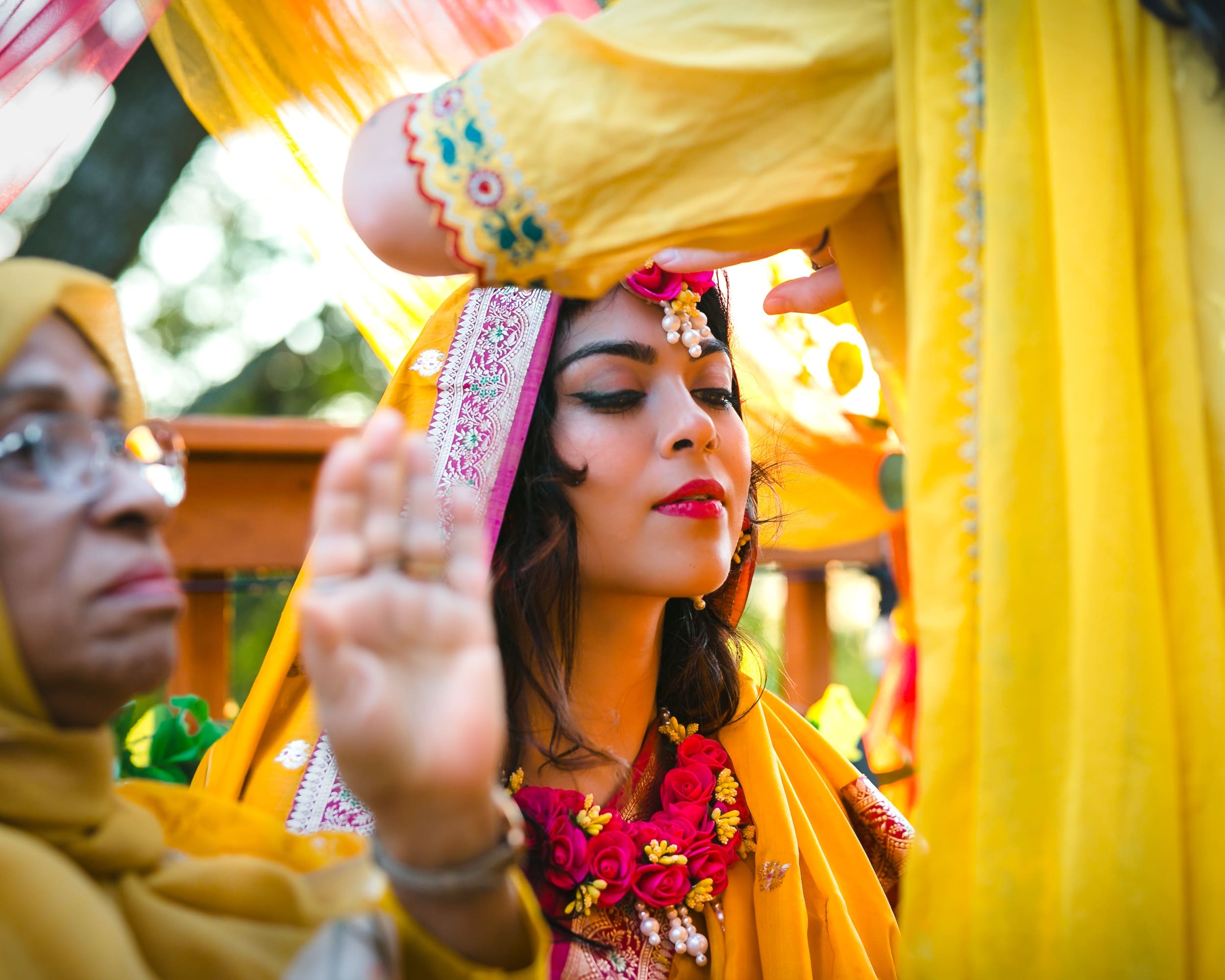 Relatives applying turmeric to the bride’s face during her Gaye Holud in oshawa, Ontario by Toronto Wedding Photographer